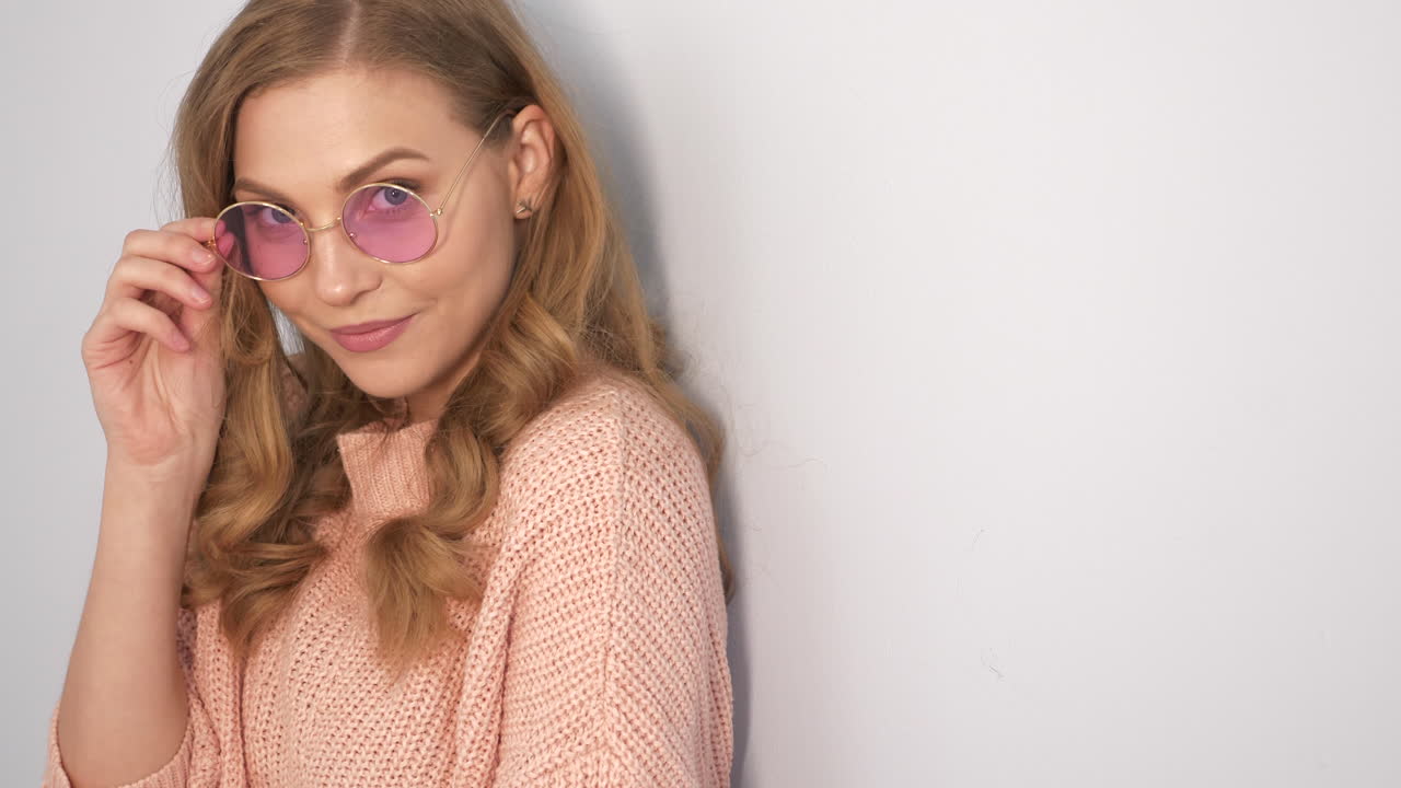 Woman wearing pink sweater and round sunglasses