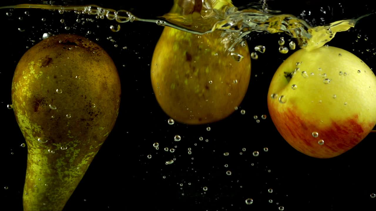 Pere e mele cadono in acqua. Rallentatore.