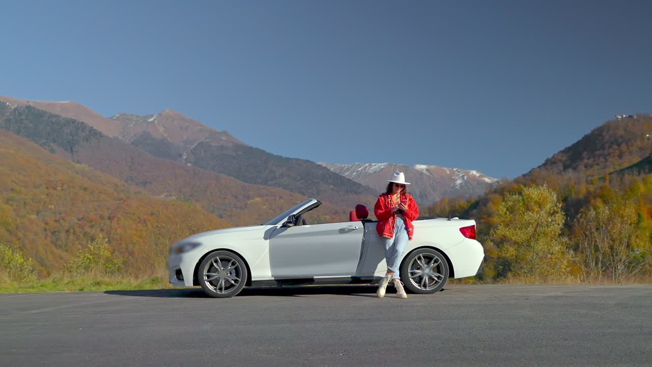 여성이 컨버터블 자동차로 경치 좋은 도로 여행을 즐기고 있습니다.