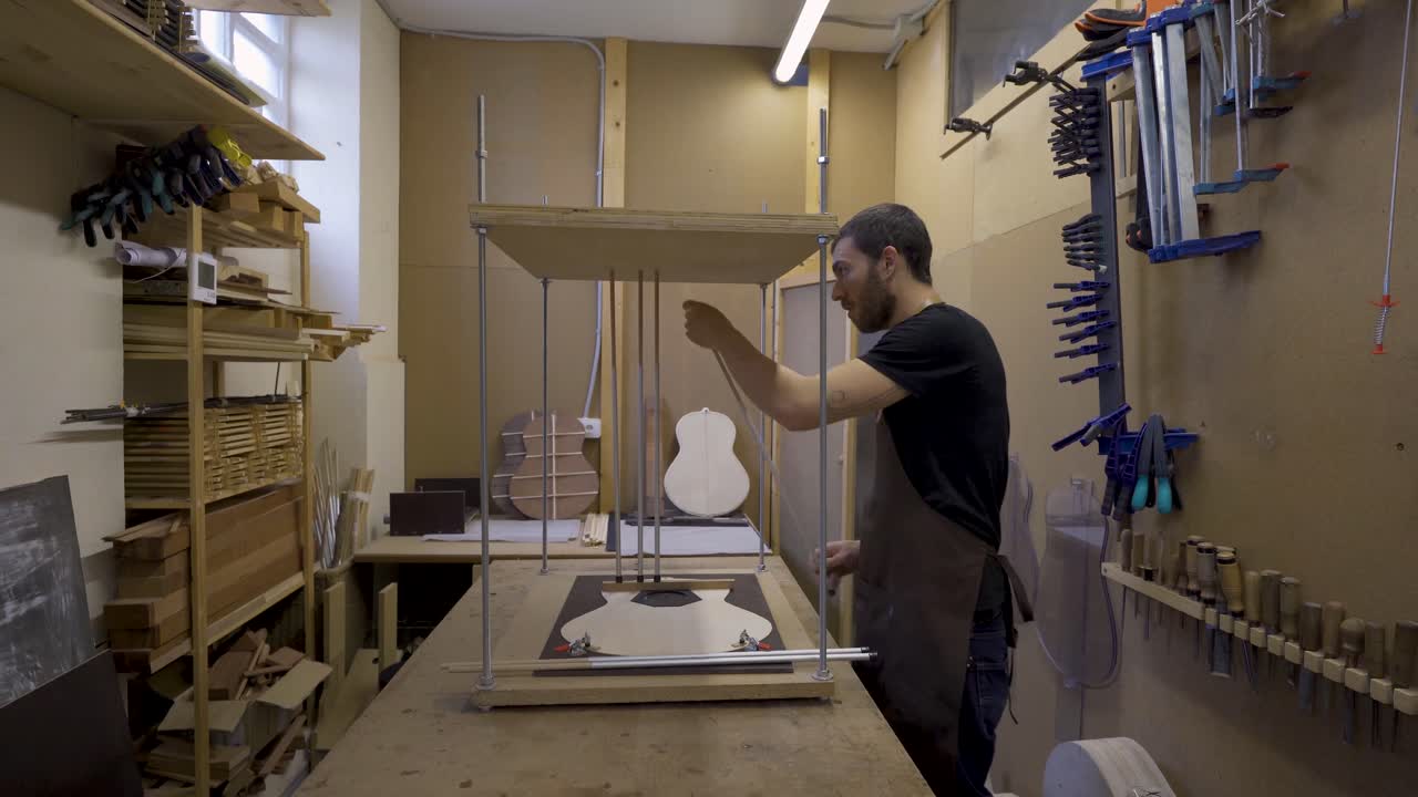 artesano instalando palos de metal mientras construye una guitarra en el taller