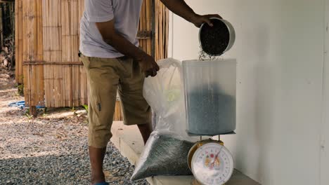 asian man weighing seeds such as pumpkin seeds, gunks, cur, cumin