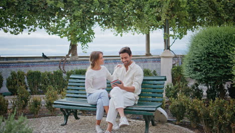 affectionate spouses embracing happily park bench. happy man woman watching book