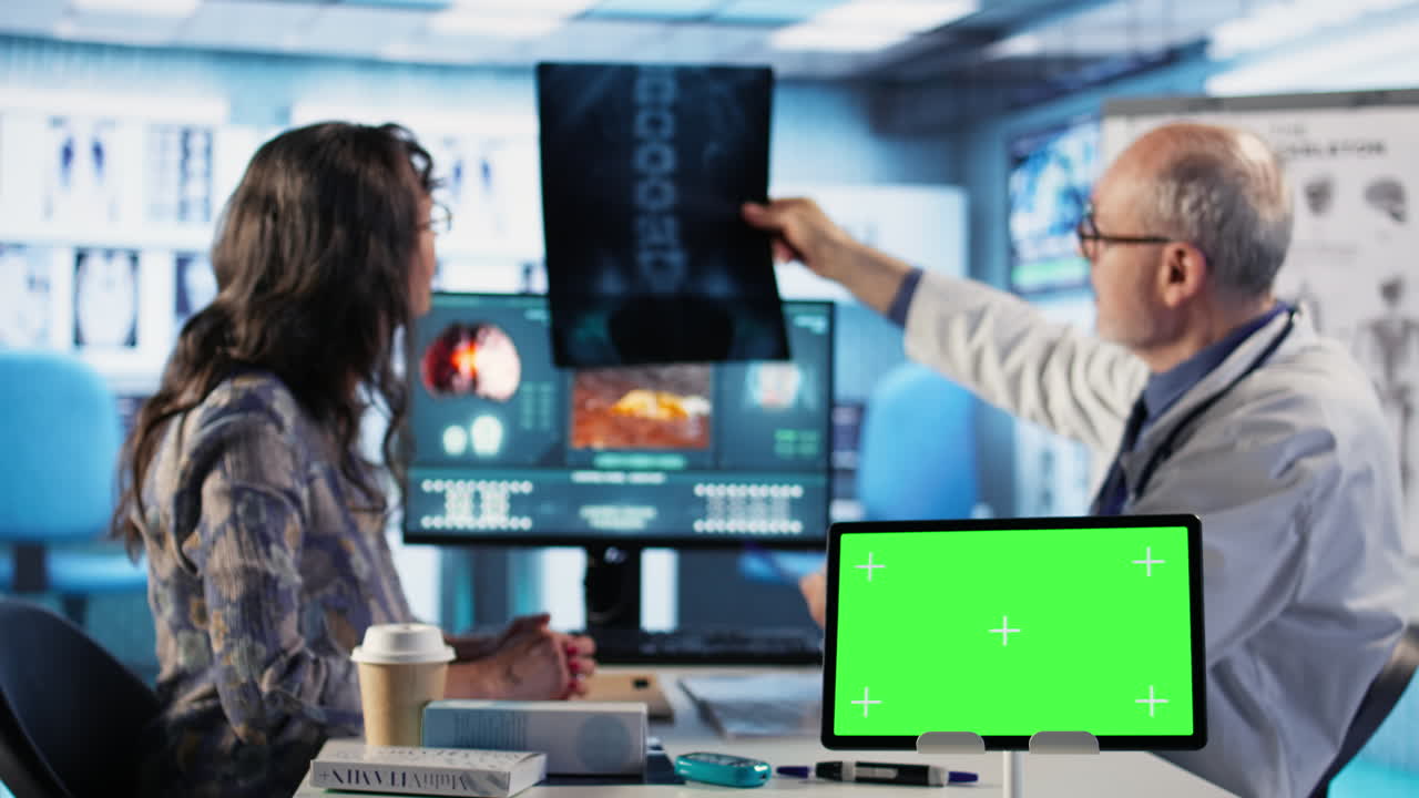 Vertical Video Senior medic talking to his female patient next to mockup green screen