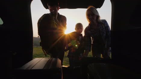 the family with the child is going on a trip together they put the bags in the trunk of the carr