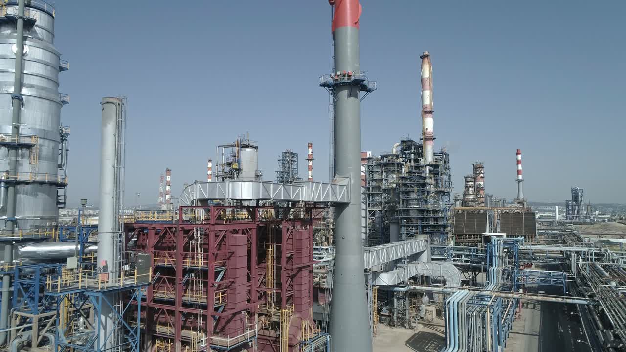 Aerial footage of a large scale Oil refinery with smoke stacks