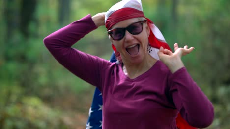 closeup of pretty, blonde woman wrapping an american flag around her head and giving the camera the “ok” or okay sign with her hand