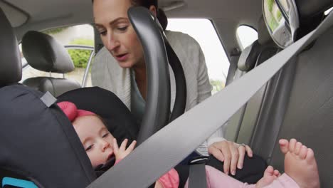 Caucasian-mother-kissing-her-baby-in-safety-seat-in-the-car