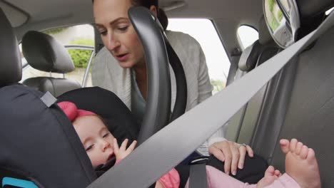 caucasian mother kissing her baby in safety seat in the car