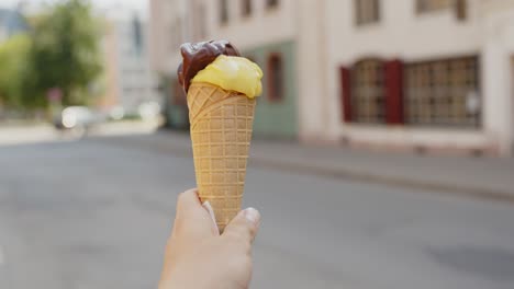 Sosteniendo-Helado-De-Gelato-Contra-Las-Vistas-De-La-Ciudad-En-El-Fondo,-De-Mano