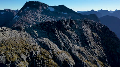 drone-shot-Milford-Sound-Gertrude-Saddle-Fiordland-National-Park,-New-Zealand-hikers-on-top