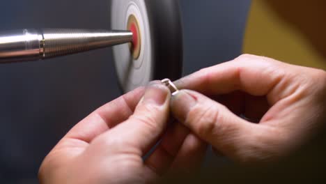 male jewelry maker hand polishing and buffing a silver ring in a jewellery making workshop