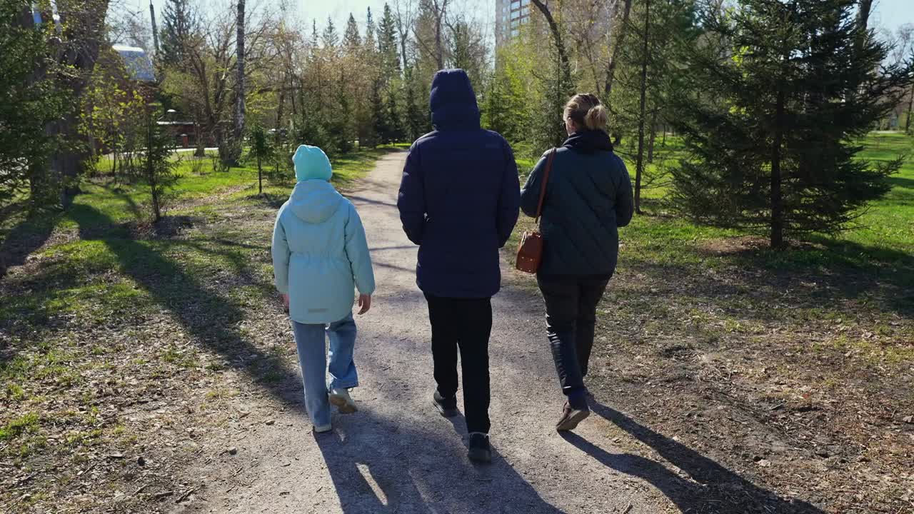 Tre persone che camminano su un sentiero in un parco soleggiato