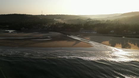 Aerial-shot-of-a-single-person-walking-on-the-beach-during-sunrise