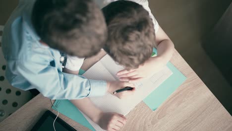 High-angle-shot-Children-do-school-homework-the-elder-brother-in-headphones-2