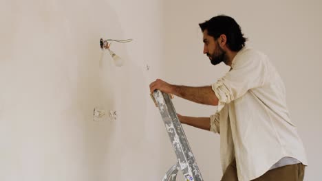 a man with a large brush applying limewash paint on the wall