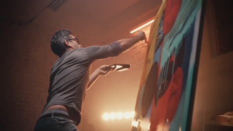 artist painting a large abstract canvas in a studio
