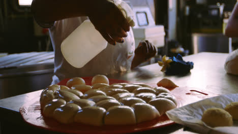 chef spraying water on dough 4k