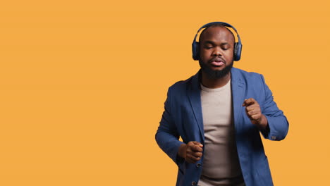 man having fun, dancing on rhythm, listening to headphones, studio background