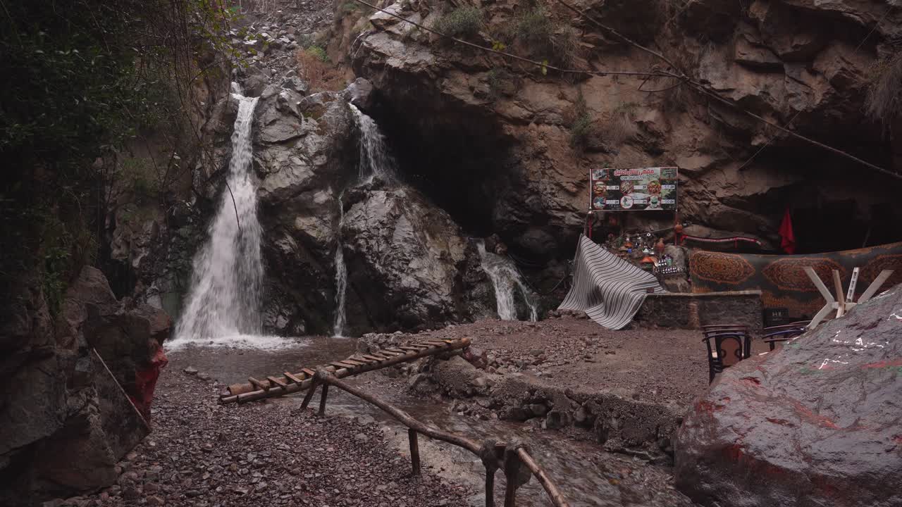 The Cascade Imlil is shrouded in a cloudy, moody atmosphere at dusk, its waters flowing gently in the fading light of Morocco’s evening