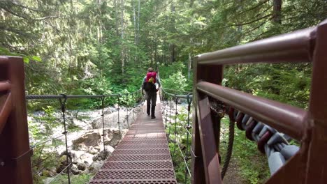 alejándose de la cámara en un puente de cable en la isla de vancouver