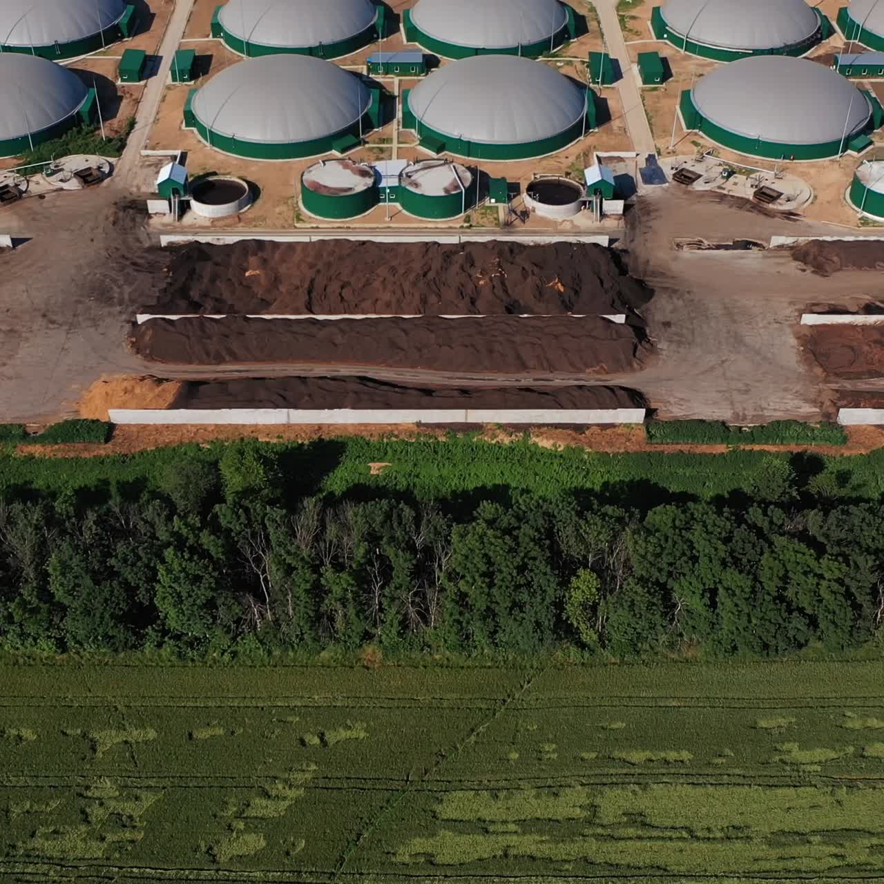 The territory of modern biogas production enterprise. Flight over green plantations and big storage tanks. Ecological production concept