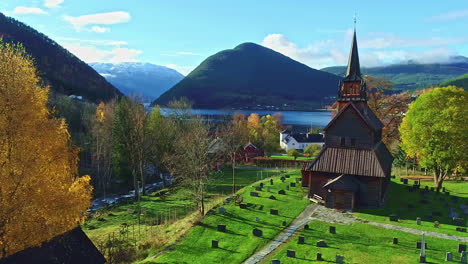 Vista-Aérea-Pasando-Por-Una-Iglesia-De-Madera,-Follaje-De-Otoño-En-Los-Fiordos-Del-Centro-De-Noruega