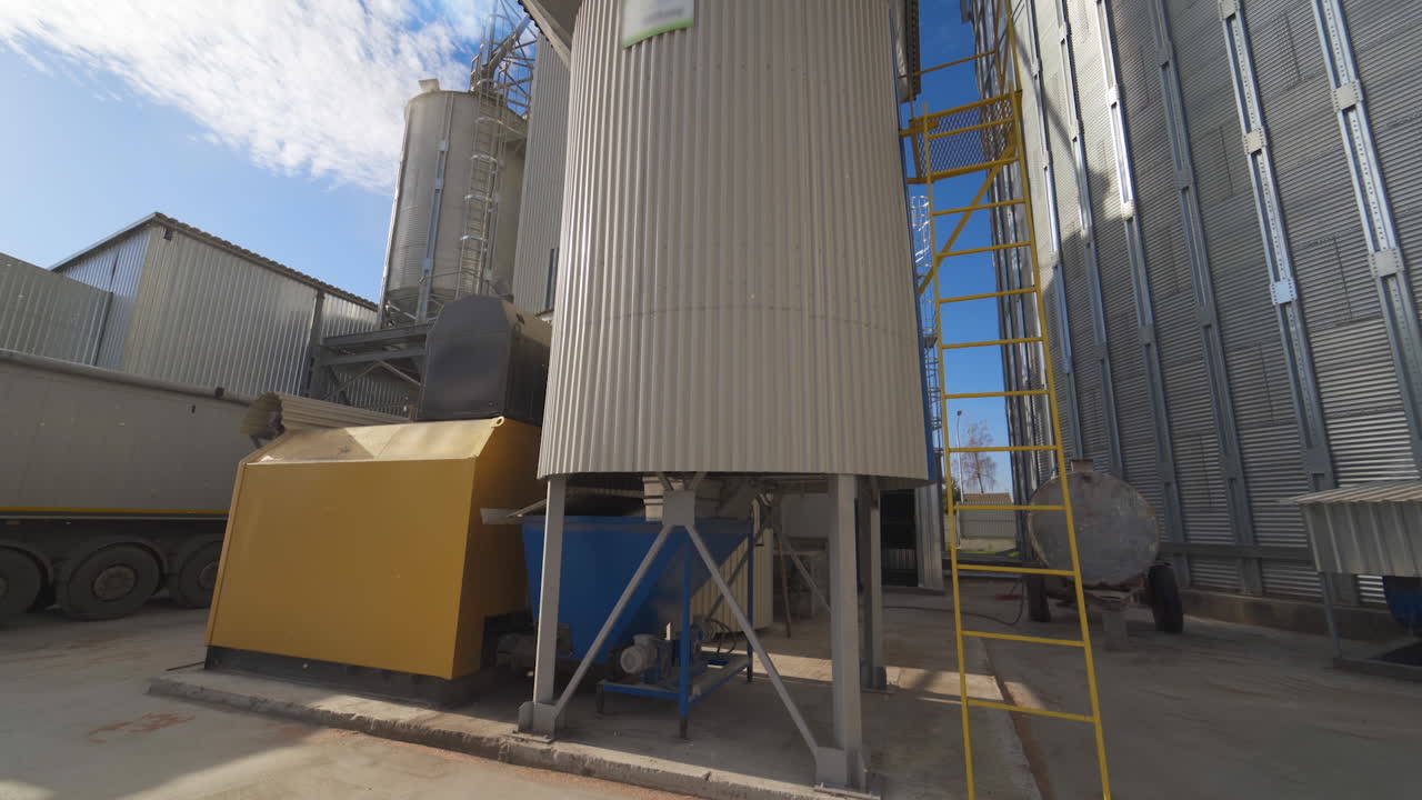 Metal equipment on the large agricultural factory. Exterior of agricultural complex with huge grain elevators. Modern processing plant.