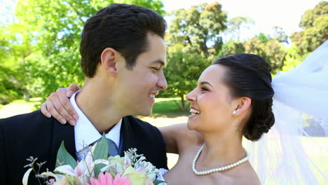 recién casados felices de pie en el parque