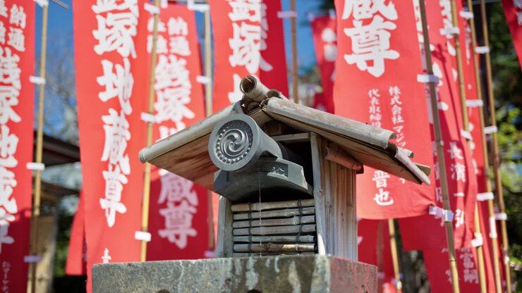 Primo piano di una piccola fontana circondata da bandiere rosse nel tempio Senso-ji ad Asakusa, Tokyo, Giappone