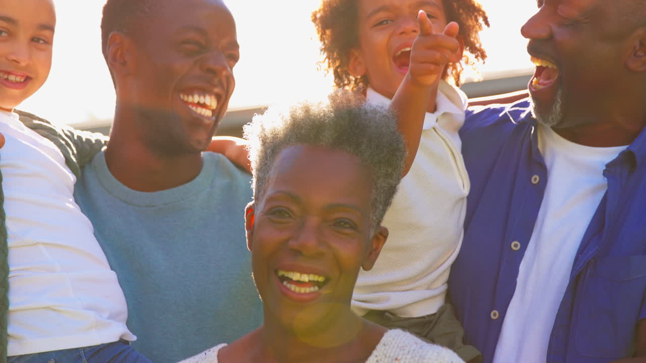 Porträt einer Mehrgenerationenfamilie draußen im heimischen Garten im Gegenlicht der Sonne