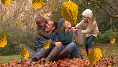 animation of orange autumn leaves falling over happy caucasian family in park