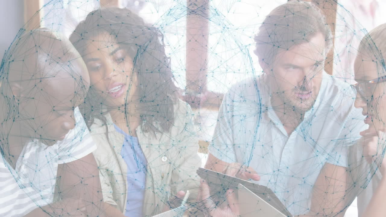 business team collaborating around table using laptop and tablet showing network graph overlay