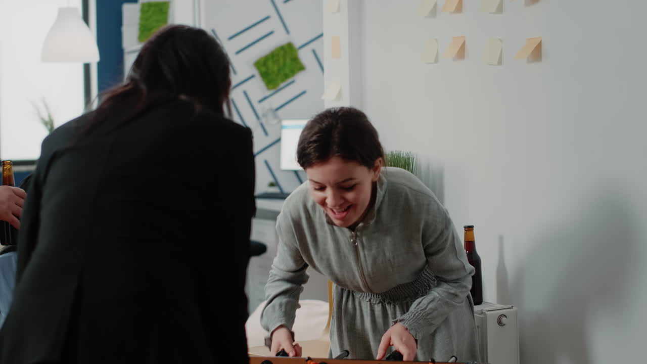 Women having fun while playing with foosball table at office