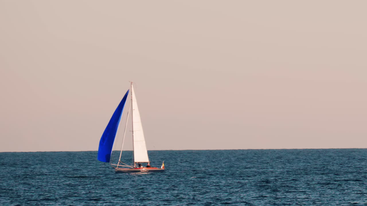 Small ship with a blue sails moving on the sea in Golfe-Juan, France