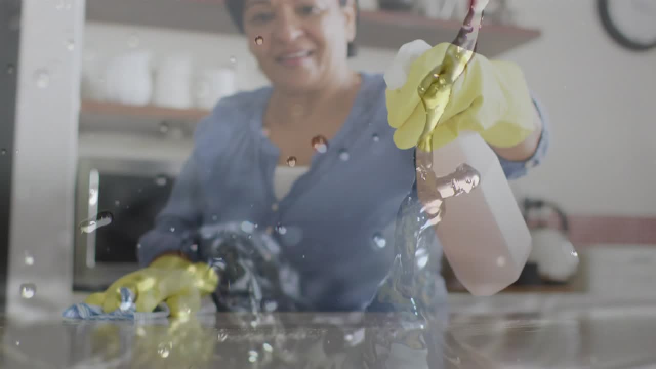 Senior woman pressing bottle nozzle, misting kitchen countertop and wiping with cloth to clean