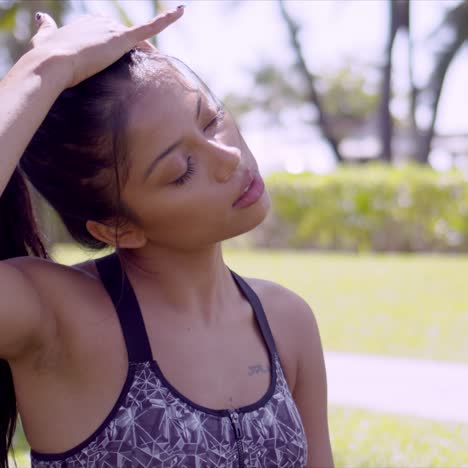 tired asian woman rubbing head with closed eyes in park