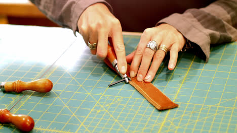 Mid-section-of-craftswoman-cutting-leather