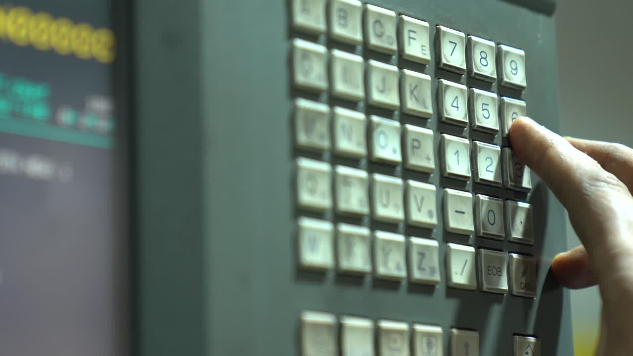 Close Up Shot Of A Machinist Pushing Buttons While Programming A CNC Machine Computer In A Workshop