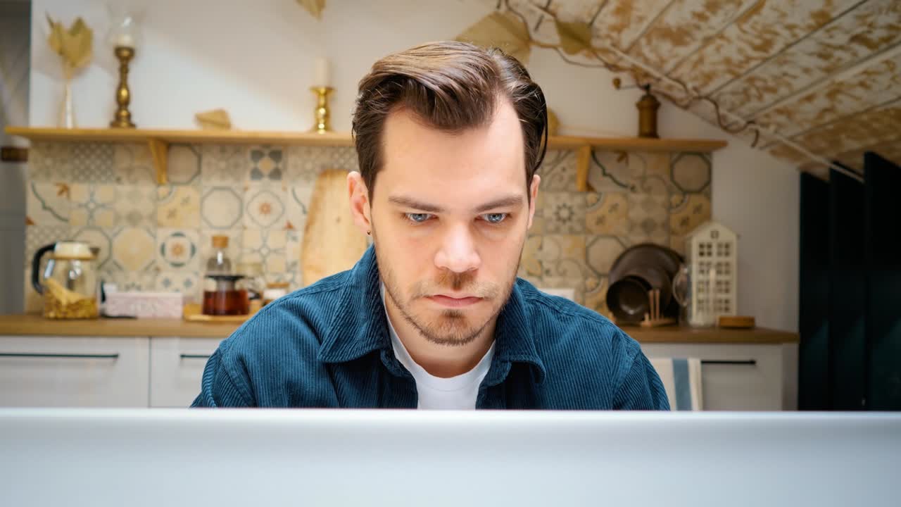 freelancer trabajando en casa en la cocina. primer plano de la cara. mira el monitor.