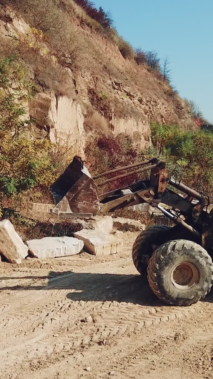 professional yellow bulldozer is working near sand quarry on the background of stones. Camera motion straight. Vertical video