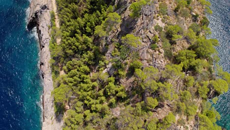 Aufschlussreiche-Aufnahme-Einer-Rauen-Klippenbucht-Mit-Bewölktem-Berg-Im-Hintergrund-Und-Dem-Anker-Einer-Yacht