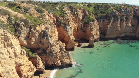 Idyllic-golden-Lagos-coast-washed-by-Algarve-stunning-warm-sea,-Portugal---Aerial-low-slide-panoramic-shot