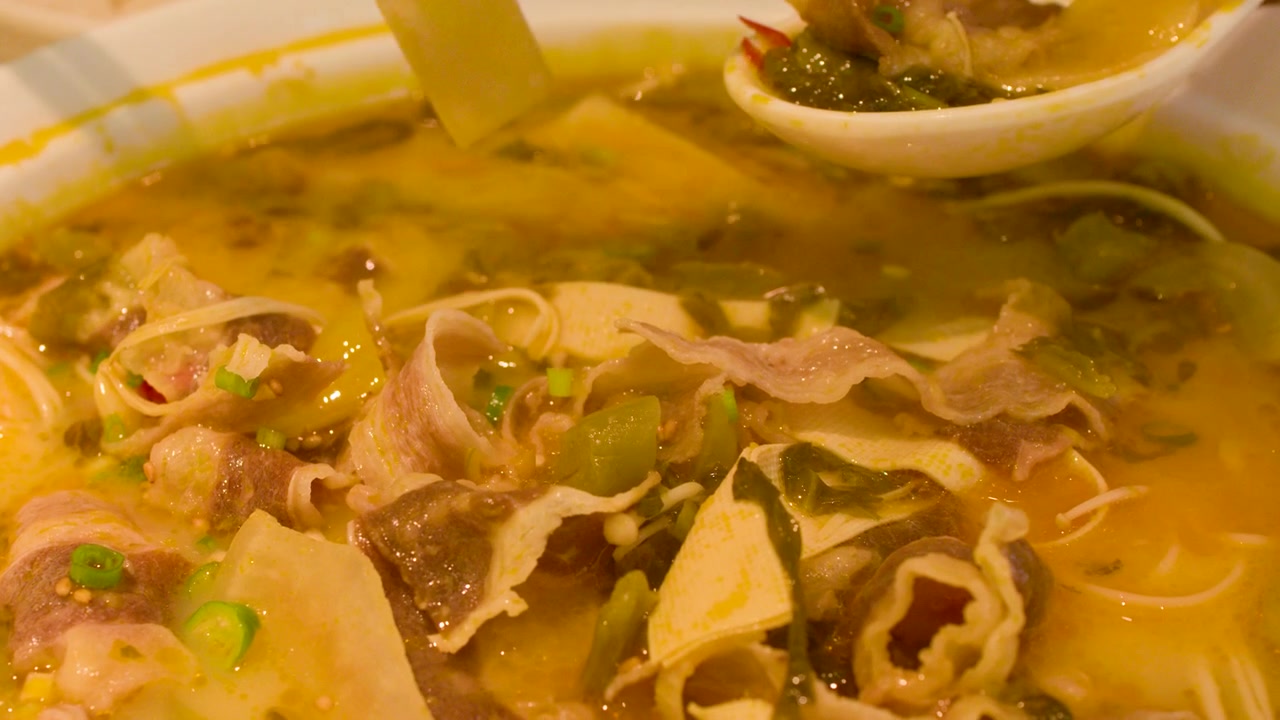 Persona che mangia una tradizionale zuppa di manzo cinese con verdure sottaceto