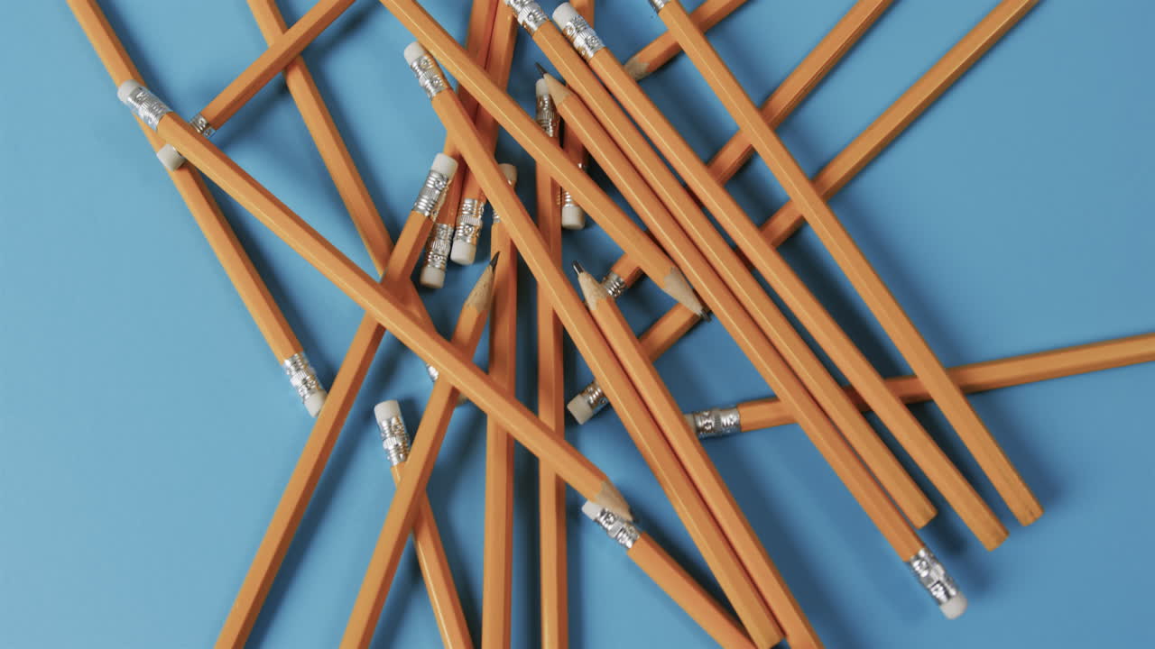 vista aérea de lápices dispersos con fondo azul, en cámara lenta