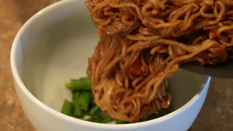 plating ramen noodles on a bed of greens - slow motion