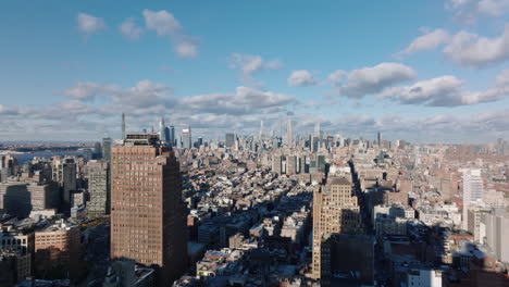 Aerial-panoramic-view-of-large-city-on-sunny-day.-Long-straight-street-among-tall-town-houses-and-skyline-with-skyscrapers.-Manhattan,-New-York-City,-USA