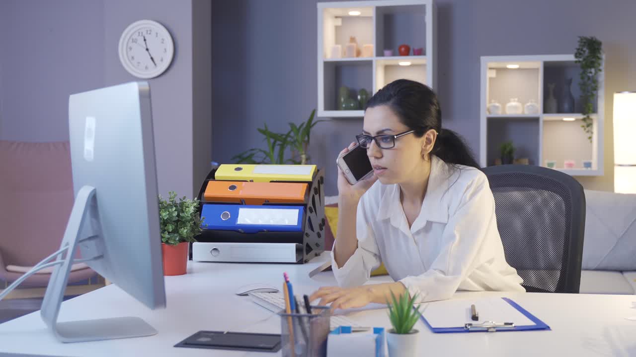 mujer de negocios hablando por teléfono y mirando la computadora.