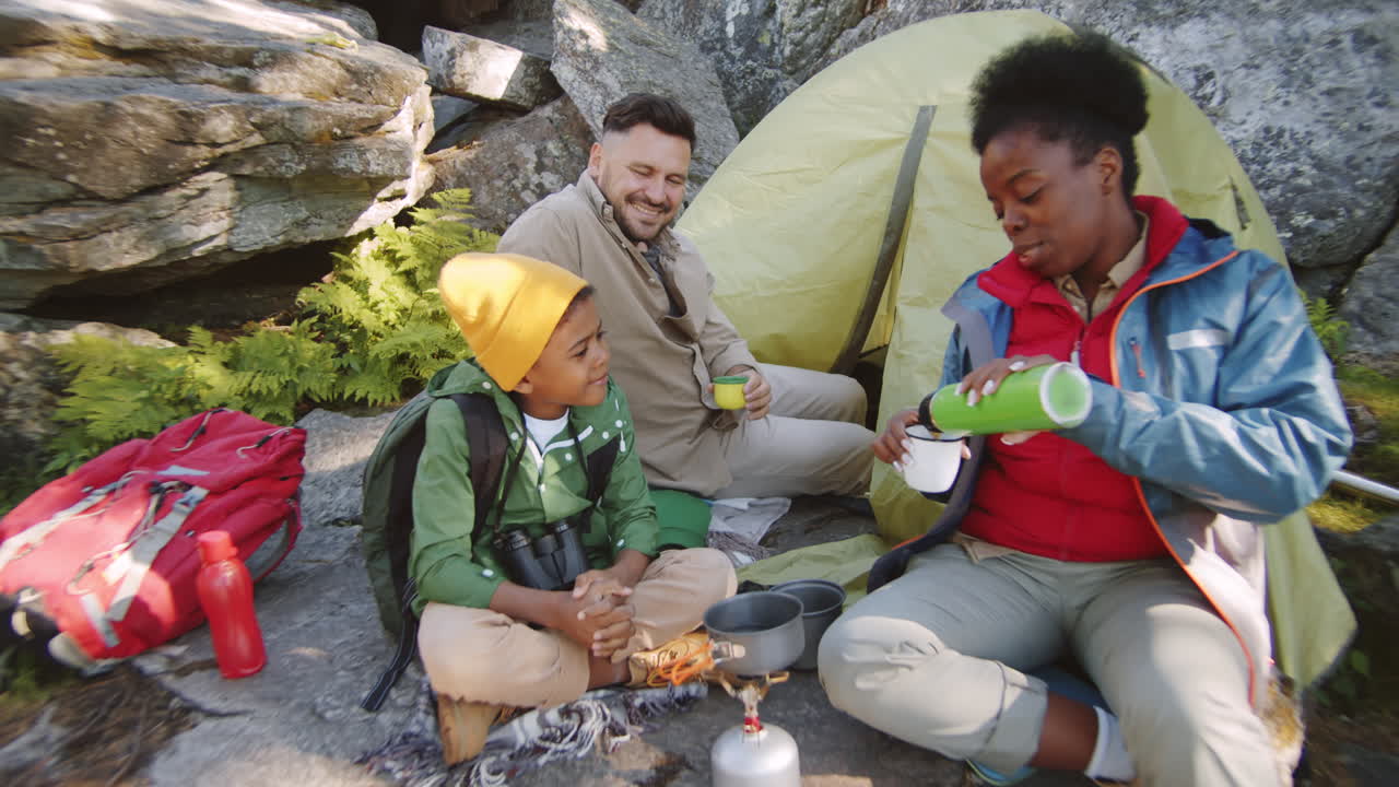 Glad mangfoldig familie drikker te på campingplass
