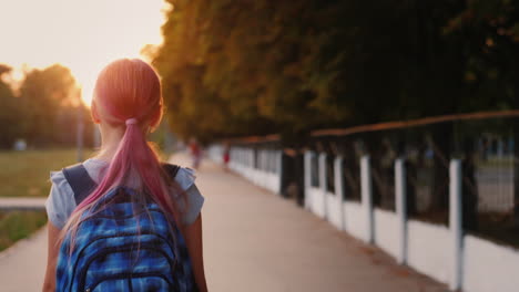 girl with school bag goes to school in the morning back to school