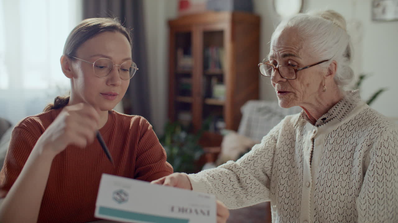 Young Woman Assisting Elderly Grandmother with Paperwork at Home